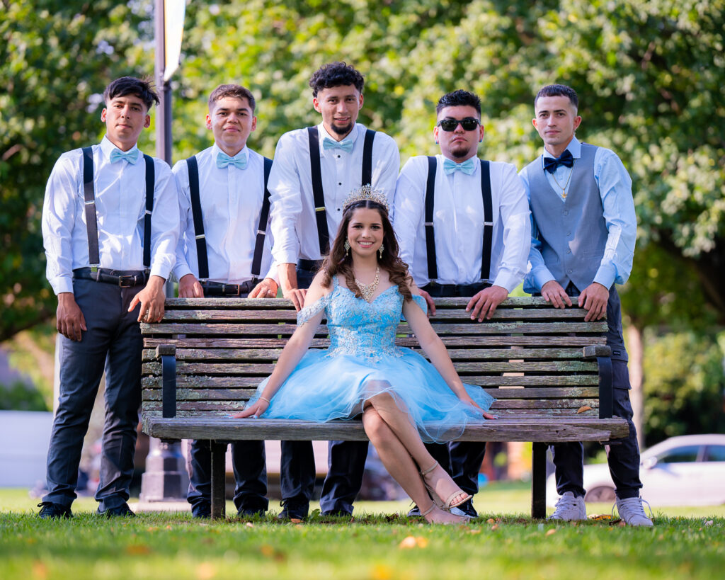 Quinceañera y su corte de honor: Un momento especial con los edecanes en New Jersey Quinceañera sentada con su corte de honor y edecanes detrás, posando para una foto grupal. Fotografía de evento social, fiesta de 15 años en New Jersey.