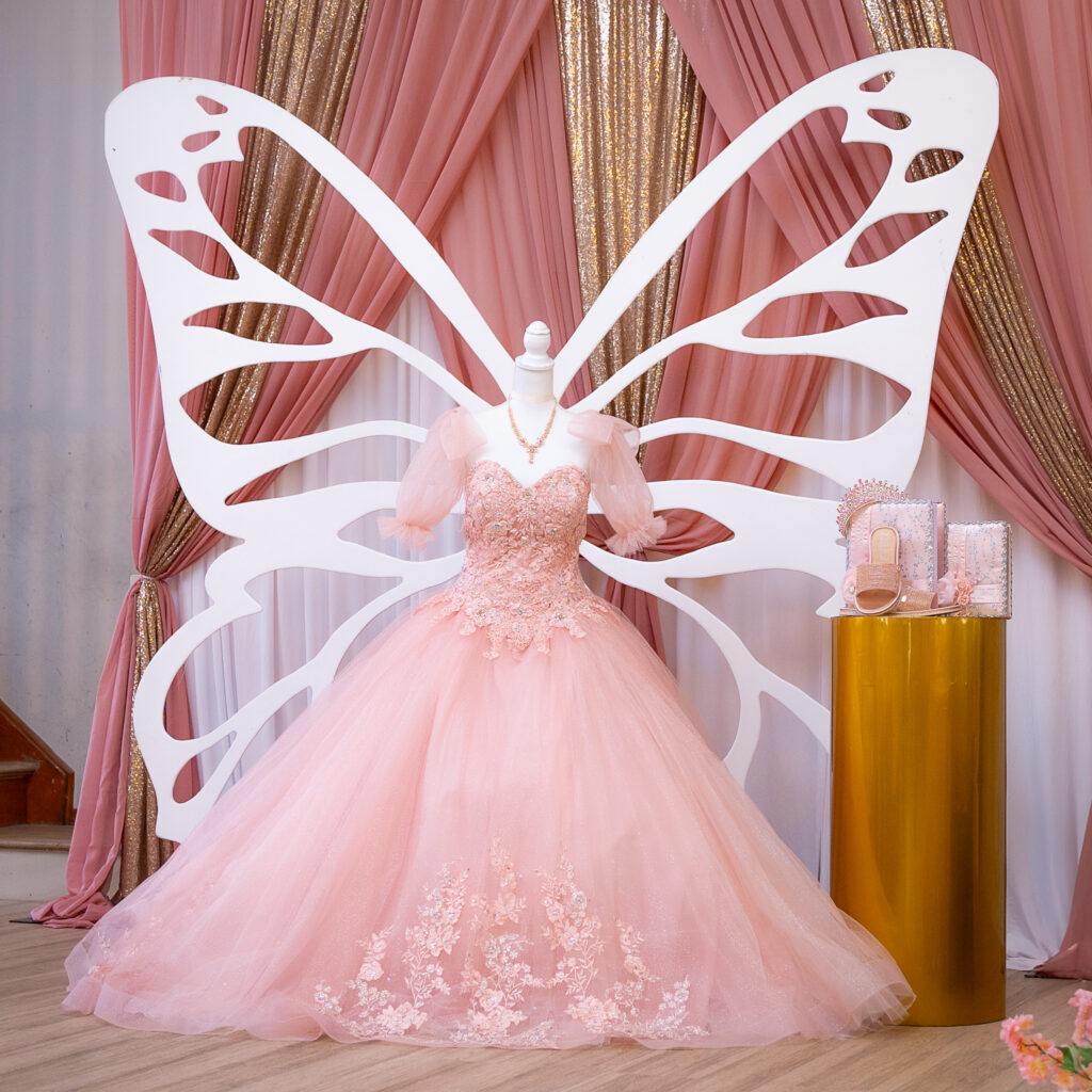quinceanera-vestido-mariposa-alas-newjersey.jpg Vestido de quinceañera con detalles de mariposa y decoración de alas en salón de eventos de New Jersey. Fotografía de evento social, quince años.